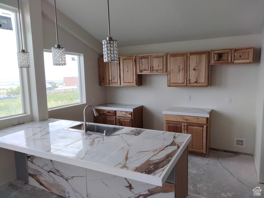 Kitchen featuring a sink, lofted ceiling, light countertops, and hanging light fixtures