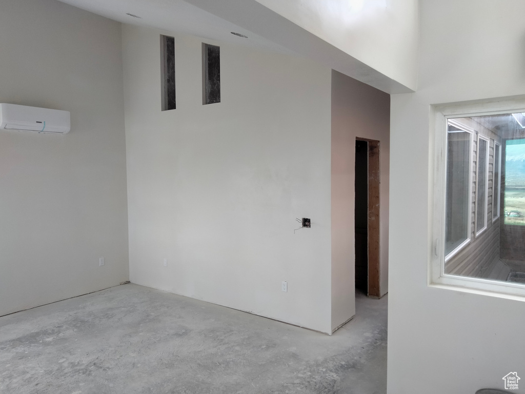 Empty room with a wall mounted air conditioner and concrete floors
