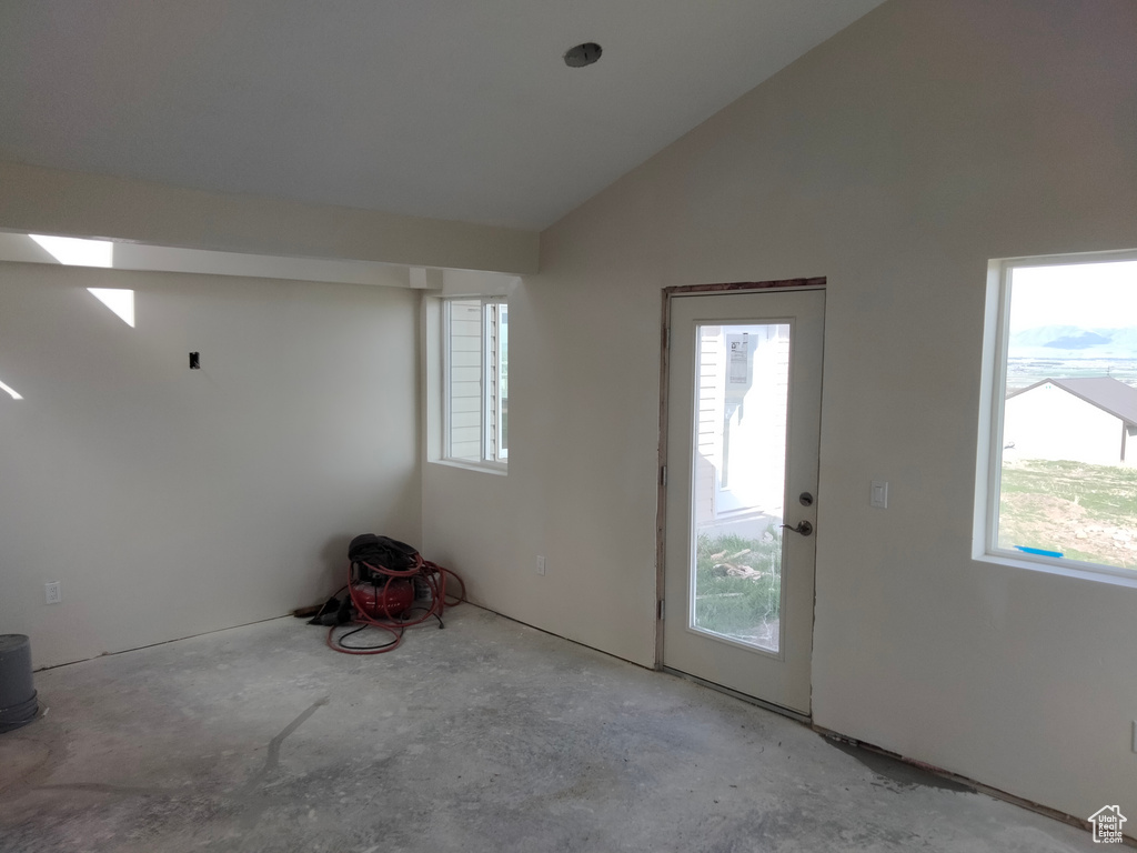 Foyer featuring healthy amount of natural light, unfinished concrete floors, and lofted ceiling