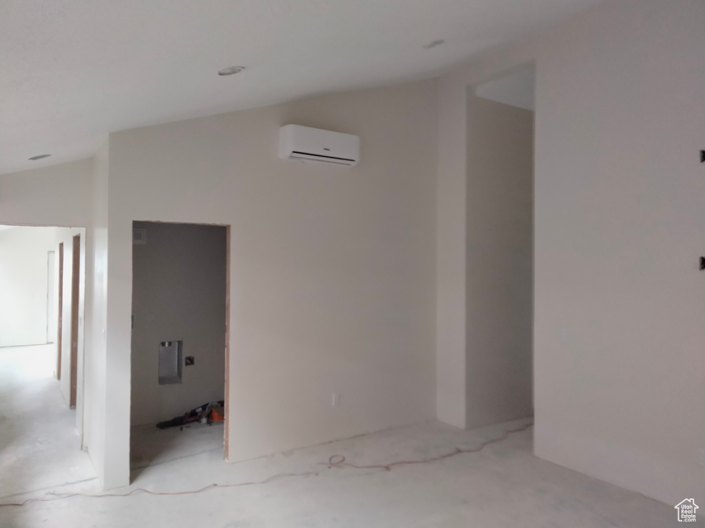 Corridor featuring an AC wall unit and lofted ceiling