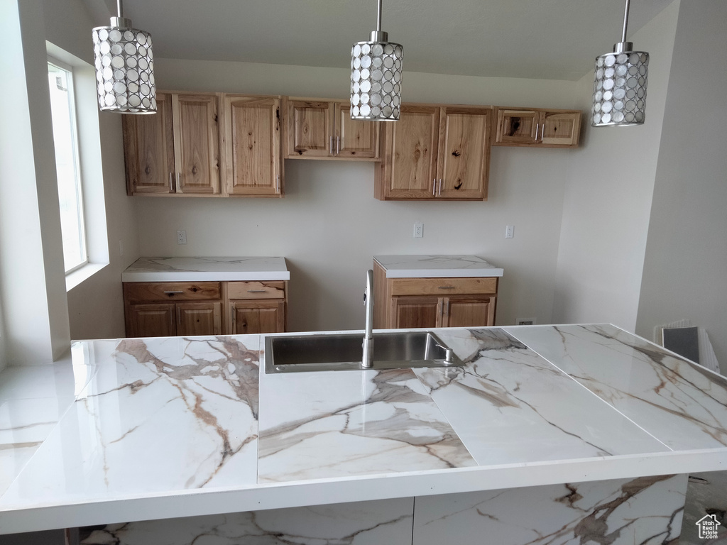 Kitchen featuring a sink, hanging light fixtures, and light stone countertops