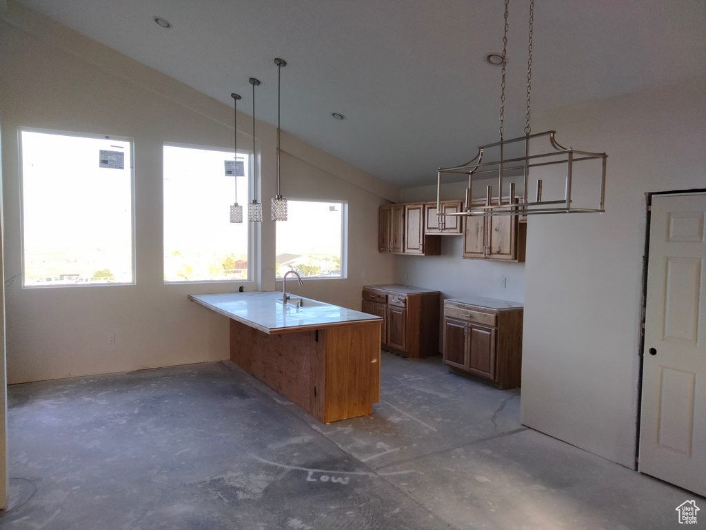 Kitchen with vaulted ceiling, a sink, concrete floors, brown cabinetry, and a peninsula