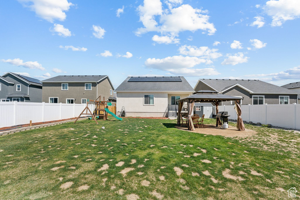 Rear view of property with a gazebo, a playground, a residential view, stucco siding, and a patio area