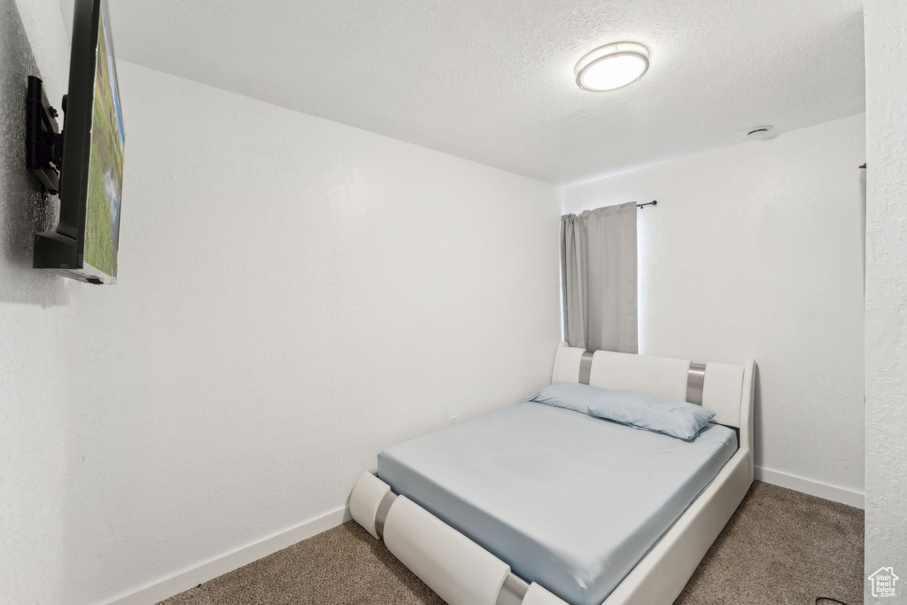 Bedroom featuring carpet flooring, baseboards, and a textured ceiling