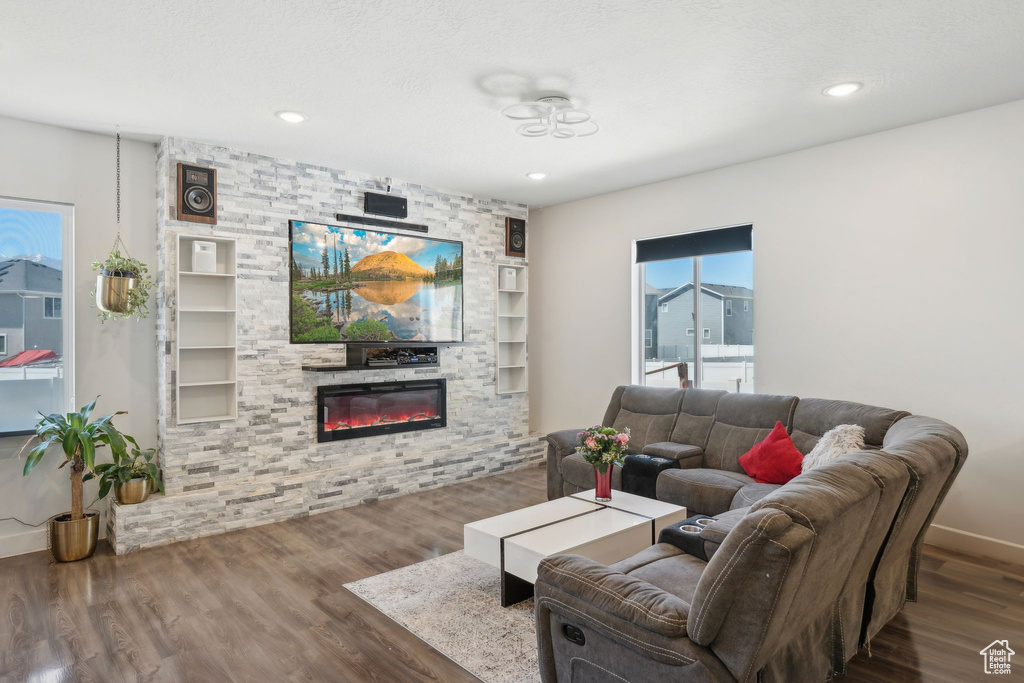 Living room featuring a stone fireplace, wood finished floors, recessed lighting, and baseboards