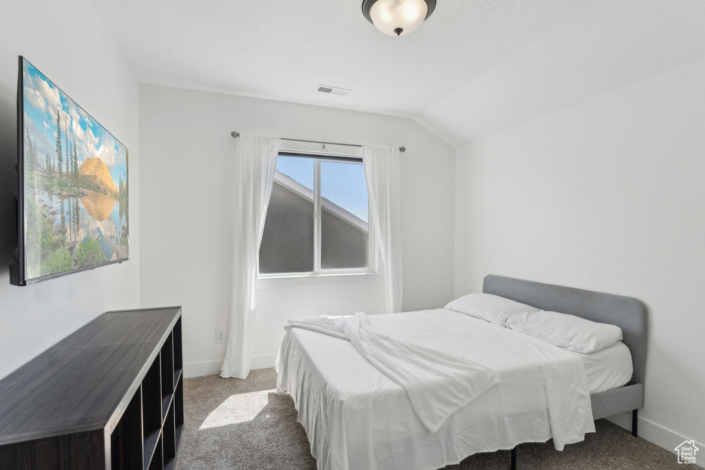 Bedroom featuring carpet floors, baseboards, and vaulted ceiling