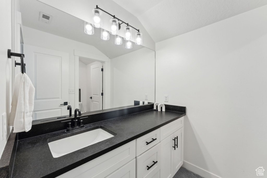 Bathroom featuring vaulted ceiling, vanity, and baseboards