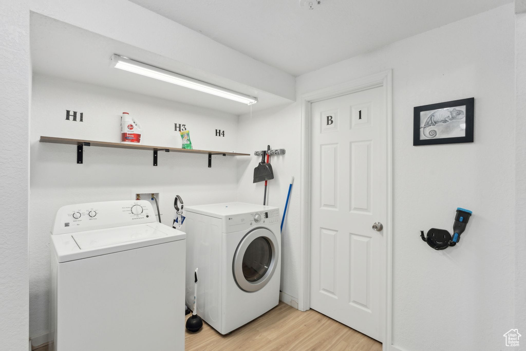 Laundry area with independent washer and dryer and light wood finished floors