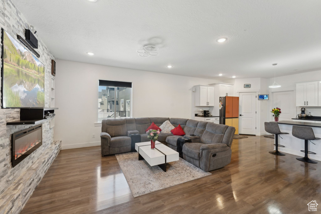Living area featuring dark wood-type flooring, a stone fireplace, recessed lighting, plenty of natural light, and baseboards