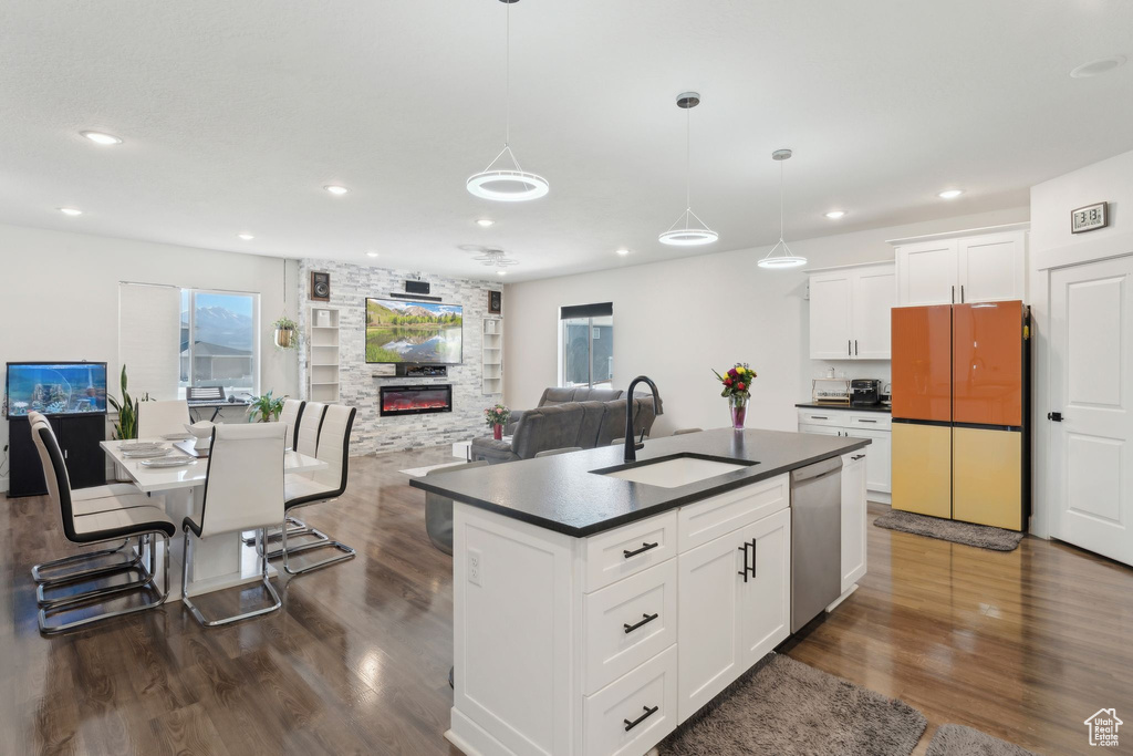 Kitchen featuring a sink, freestanding refrigerator, dark countertops, stainless steel dishwasher, and plenty of natural light