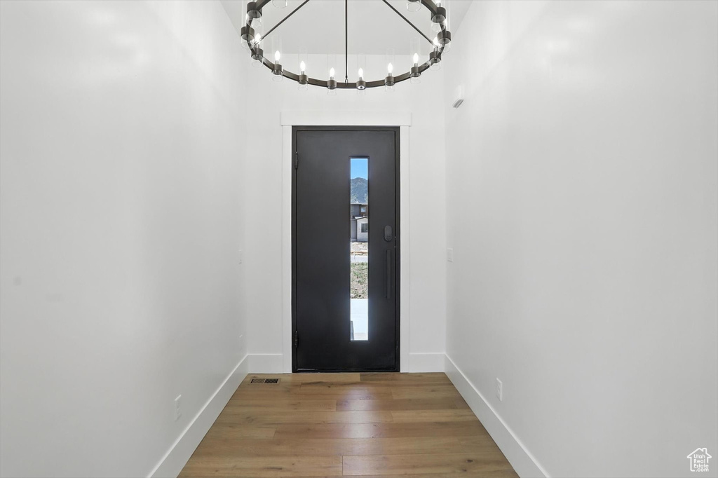 Entrance foyer with wood finished floors and a chandelier