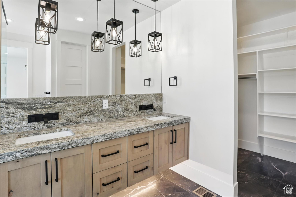Bathroom with marble finish flooring, double vanity, recessed lighting, a walk in closet, and decorative backsplash