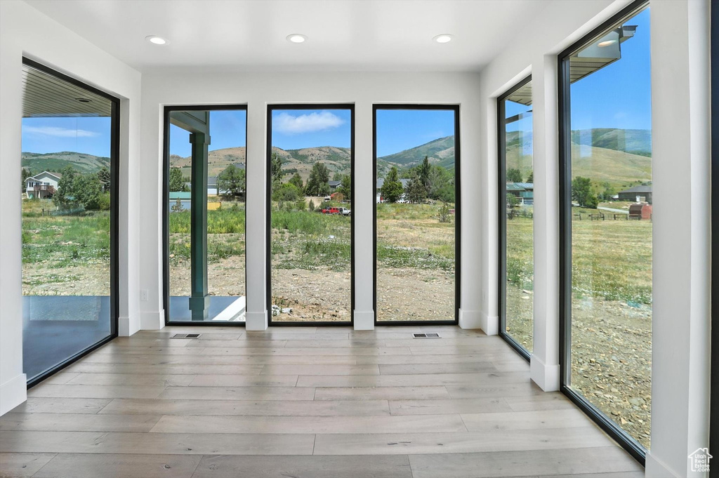 Unfurnished sunroom featuring a mountain view, wood-type flooring, and recessed lighting