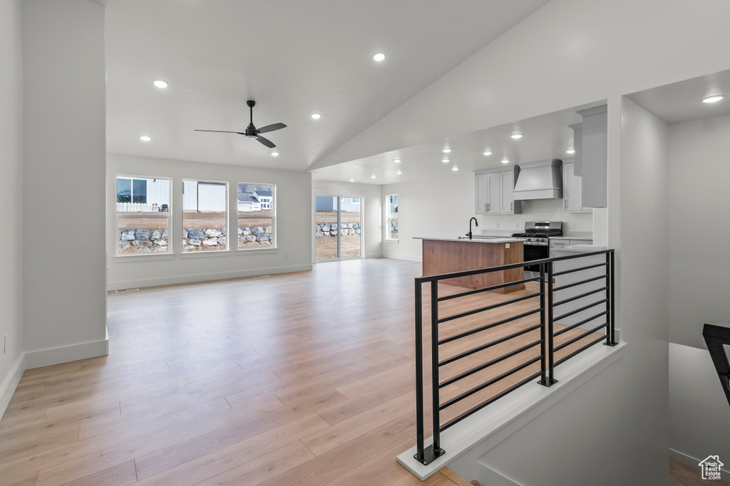 Kitchen featuring gas range, a ceiling fan, recessed lighting, open floor plan, and light wood-type flooring