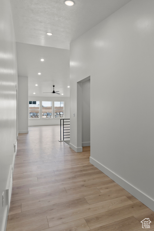 Corridor with recessed lighting, light wood-style flooring, and baseboards