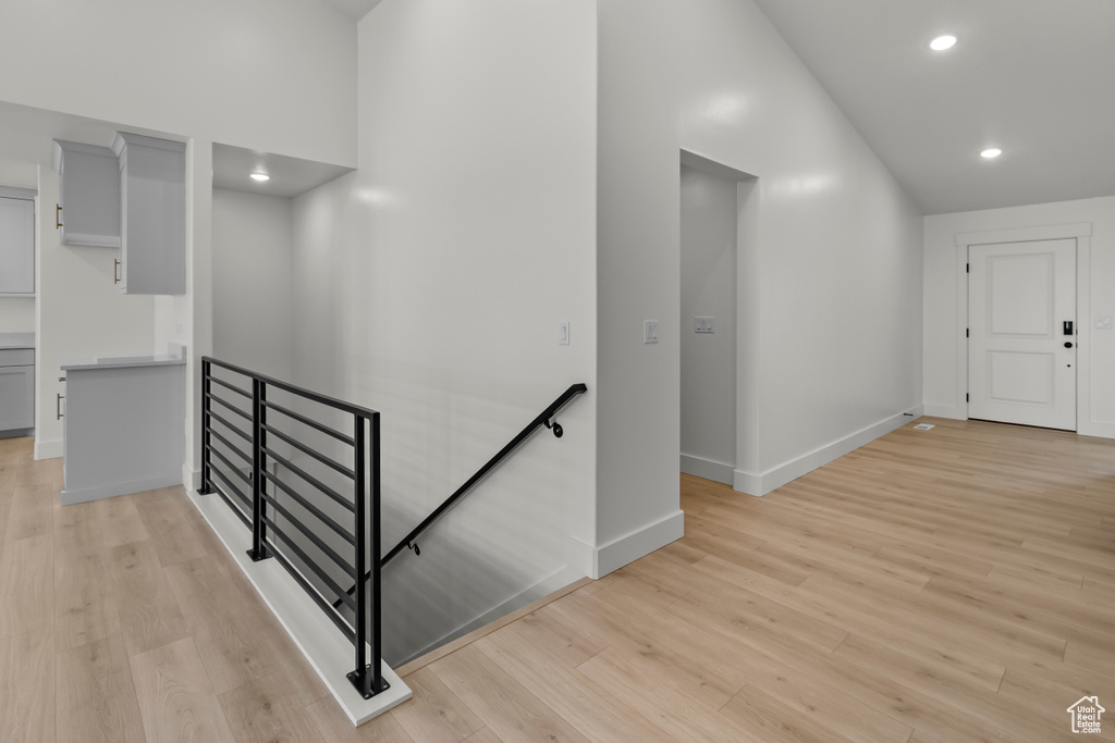 Corridor featuring an upstairs landing, light wood-style flooring, baseboards, vaulted ceiling, and recessed lighting