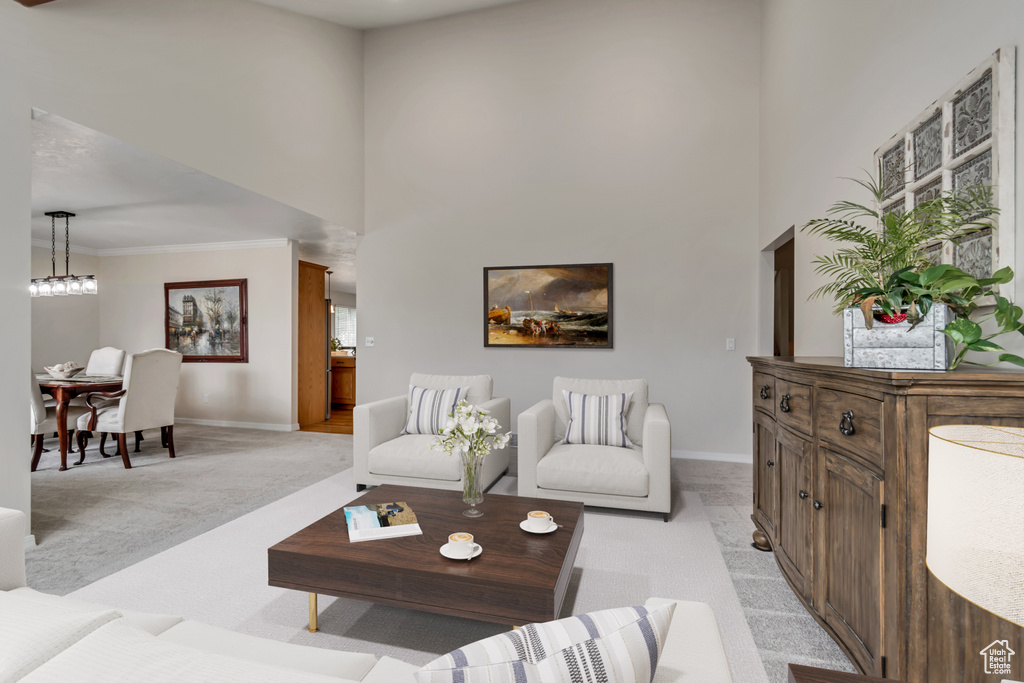 Living area featuring light carpet, baseboards, a towering ceiling, ornamental molding, and plenty of natural light