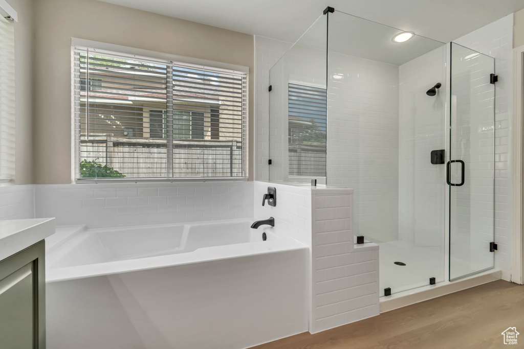Bathroom featuring a bath, a shower stall, wood finished floors, vanity, and recessed lighting