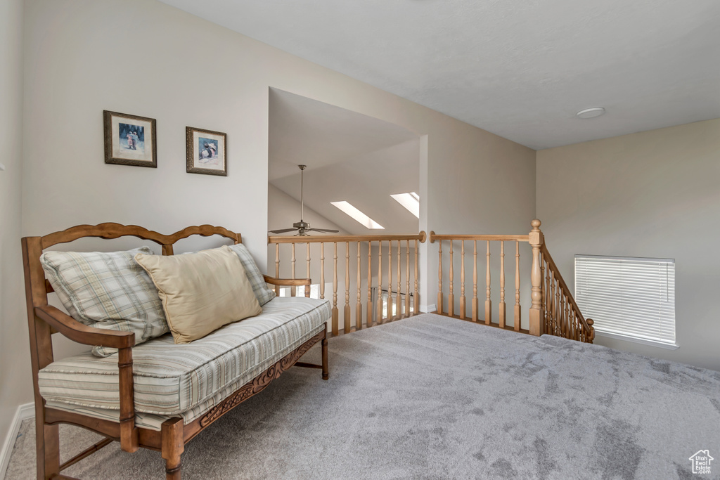 Sitting room with carpet, ceiling fan, a skylight, and an upstairs landing