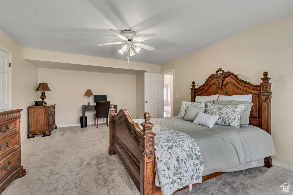 Bedroom with light colored carpet, baseboards, ceiling fan, and an office area