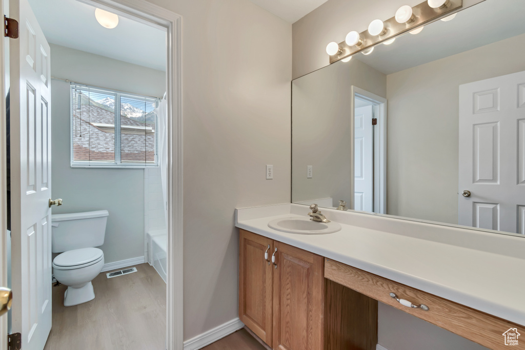 Full bathroom featuring vanity, toilet, wood finished floors, and baseboards