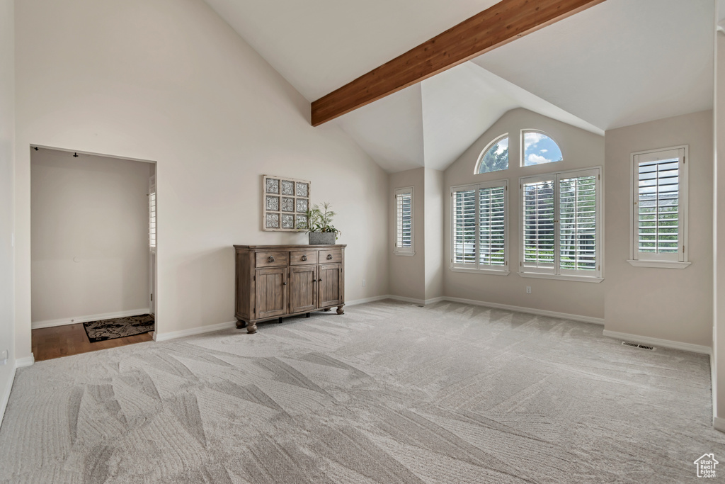 Empty room with light carpet, baseboards, high vaulted ceiling, and beam ceiling