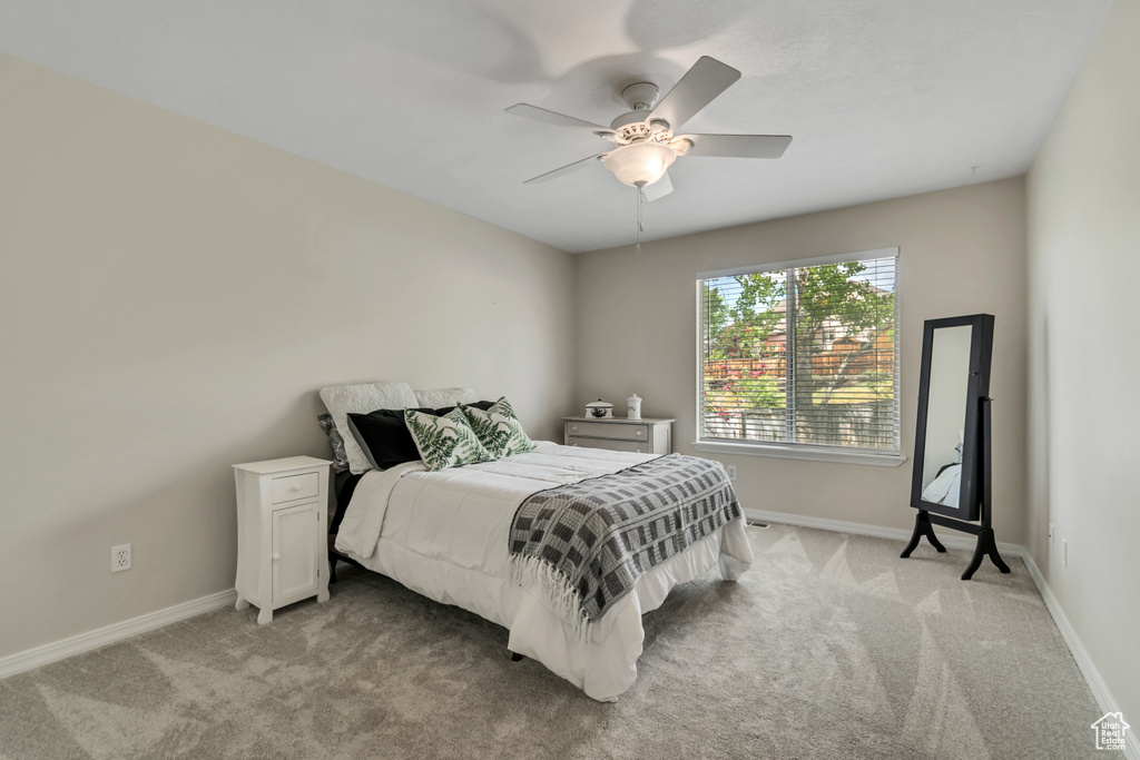 Bedroom with light carpet, baseboards, and ceiling fan