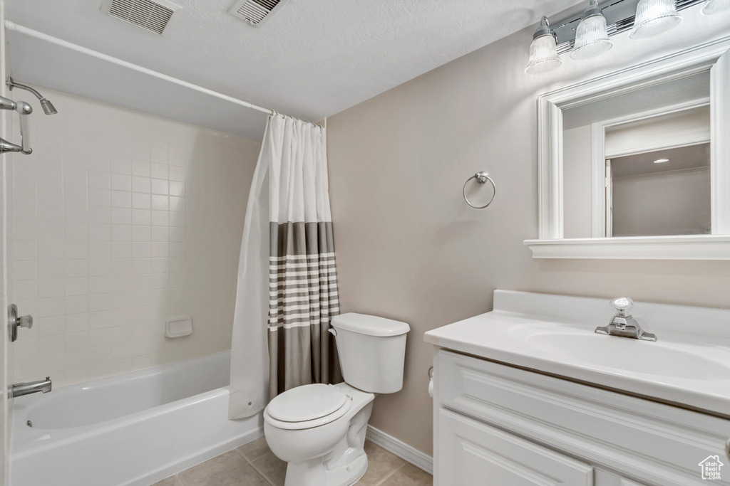 Full bathroom with vanity, tile patterned floors, toilet, shower / bath combination with curtain, and baseboards