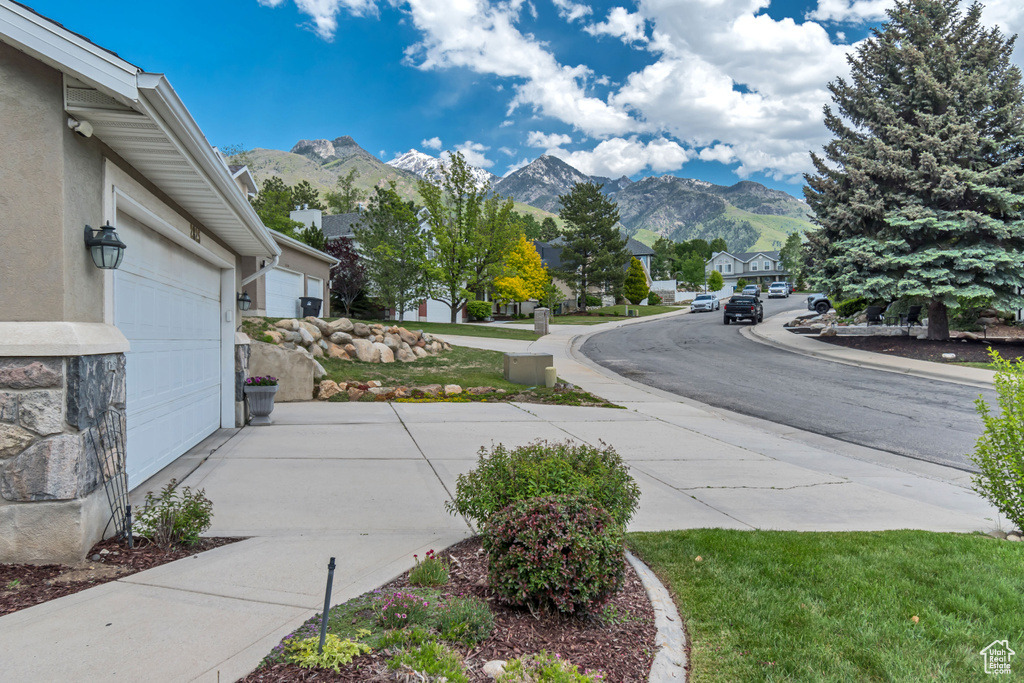 View of road featuring a mountain view, a residential view, sidewalks, and curbs
