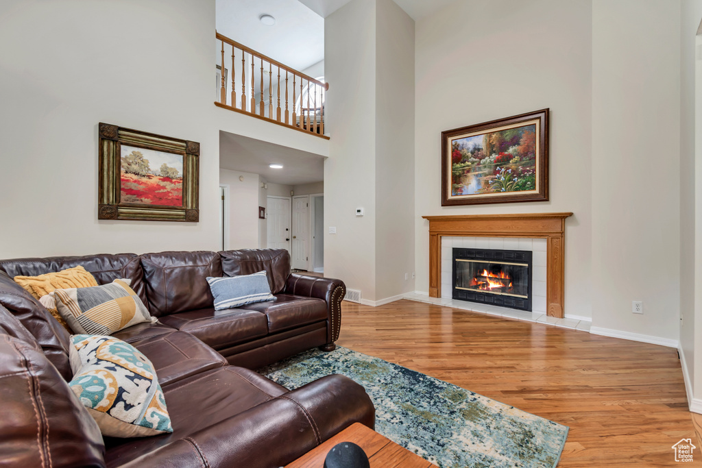 Living area with light wood-style floors, a tiled fireplace, and baseboards