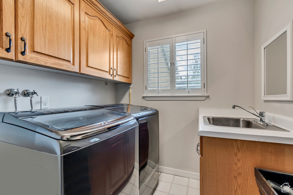 Washroom with cabinet space, washer and clothes dryer, light tile patterned floors, and baseboards