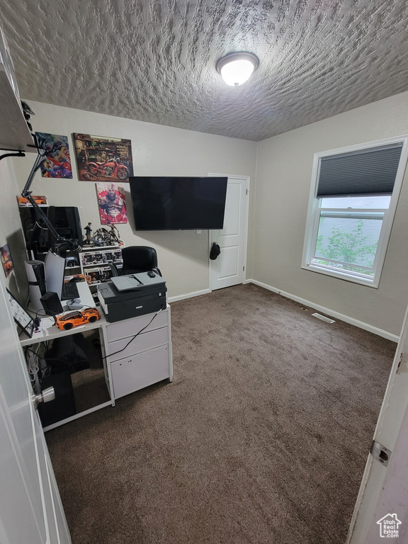 Office featuring a textured ceiling, dark colored carpet, and baseboards