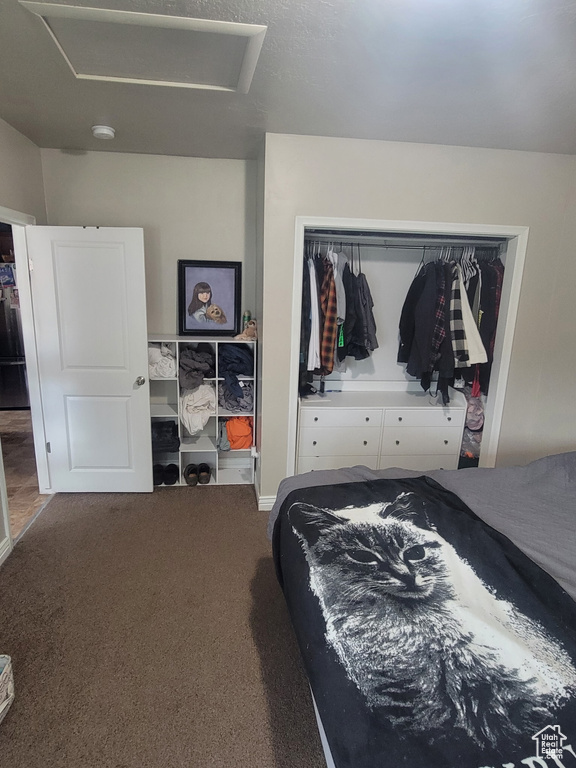 Carpeted bedroom featuring attic access, a closet, and freestanding refrigerator