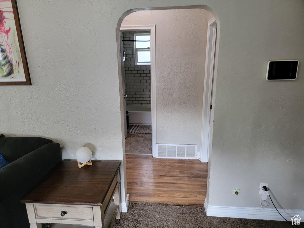 Hall with arched walkways, baseboards, and carpet floors