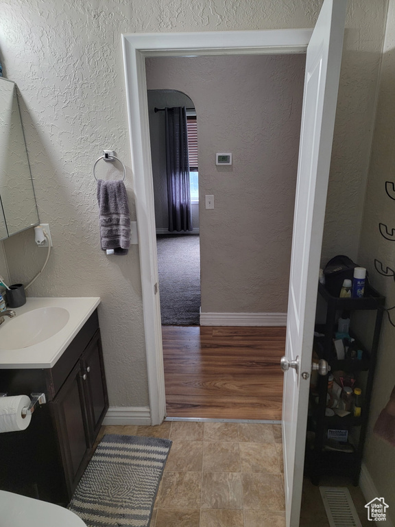 Bathroom with vanity, baseboards, and a textured wall