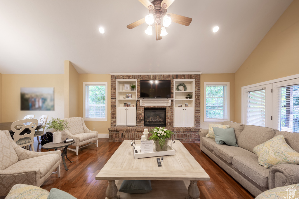 Living area with lofted ceiling, dark wood-style flooring, plenty of natural light, a ceiling fan, and baseboards