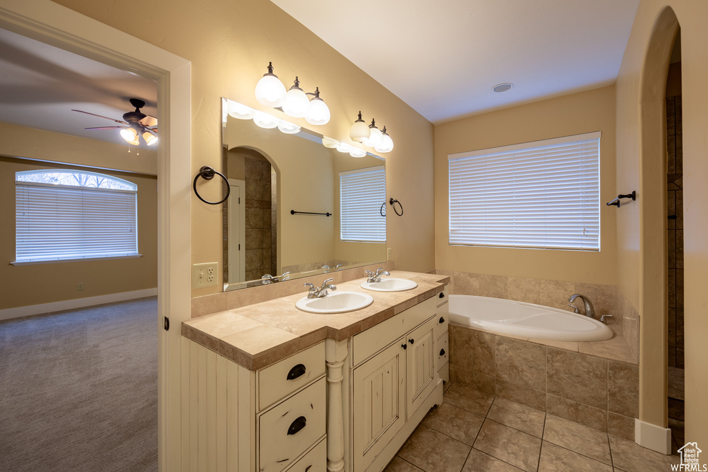 Bathroom featuring double vanity, a garden tub, a ceiling fan, and tile patterned flooring