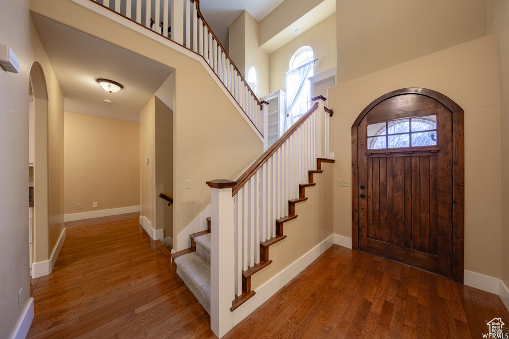 Foyer featuring arched walkways, a high ceiling, plenty of natural light, and wood finished floors