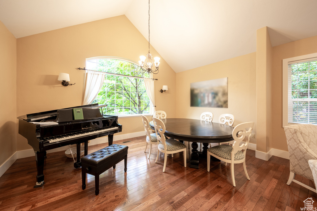 Dining area with vaulted ceiling, a chandelier, hardwood / wood-style flooring, and baseboards