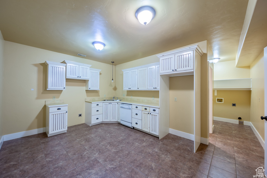 Kitchen featuring white dishwasher, white cabinetry, light countertops, and baseboards