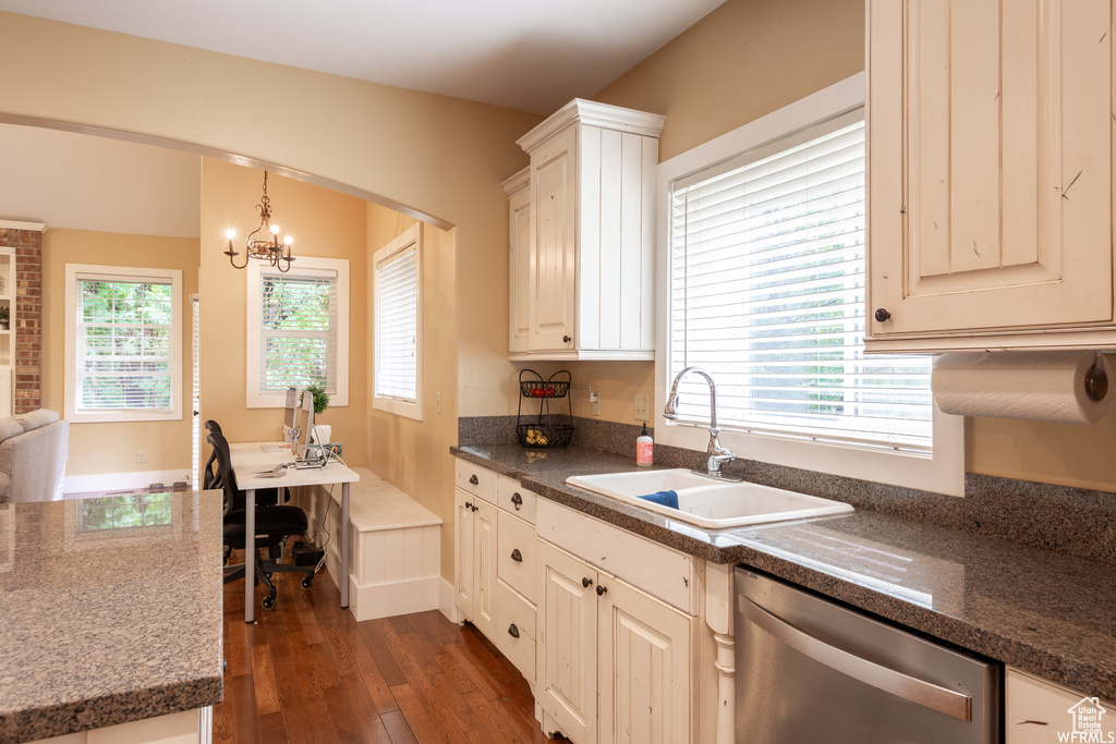 Kitchen featuring stainless steel dishwasher, a sink, dark wood finished floors, a chandelier, and arched walkways