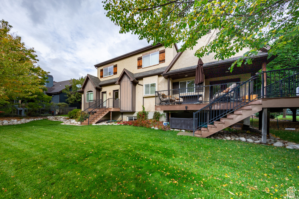 Rear view of property with stairs, a yard, stucco siding, and a deck