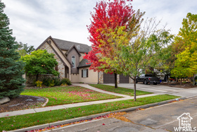 View of front facade with concrete driveway, an attached garage, a front yard, and stone siding
