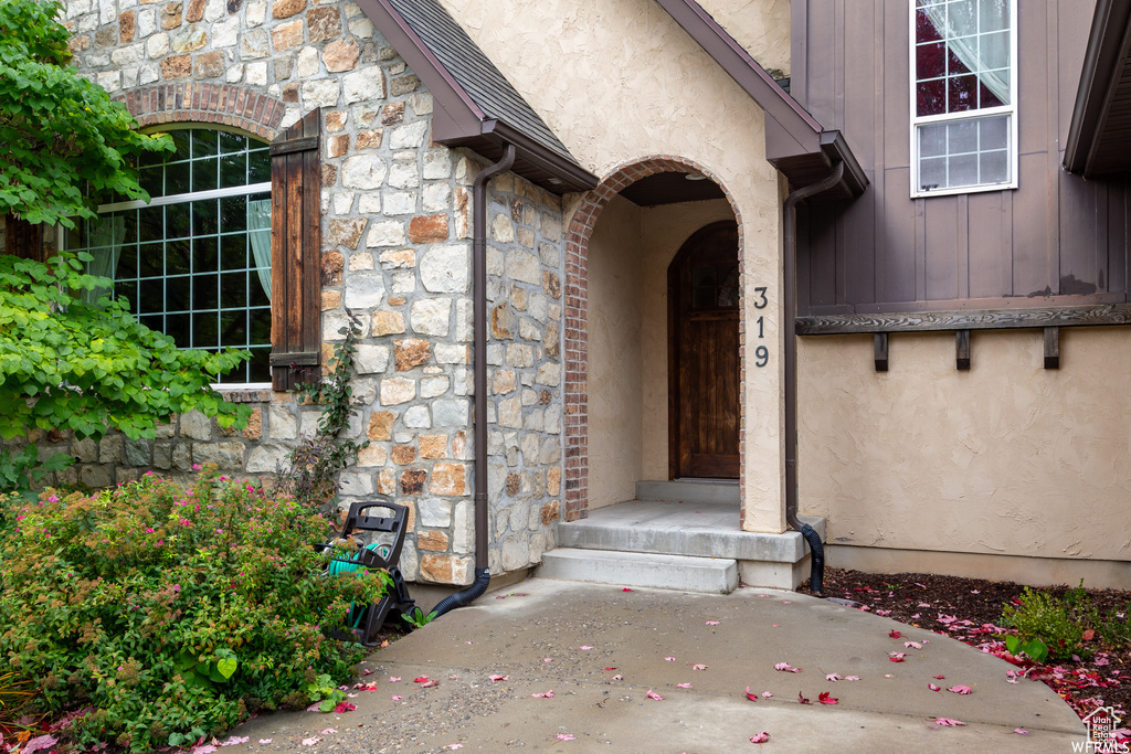 Property entrance featuring stone siding, board and batten siding, and stucco siding