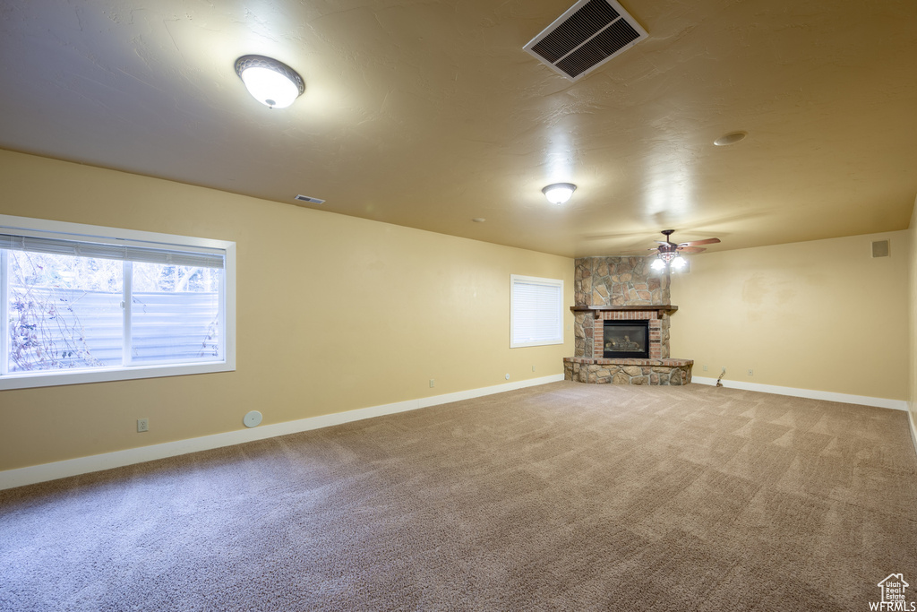 Unfurnished living room featuring a ceiling fan, carpet, and baseboards