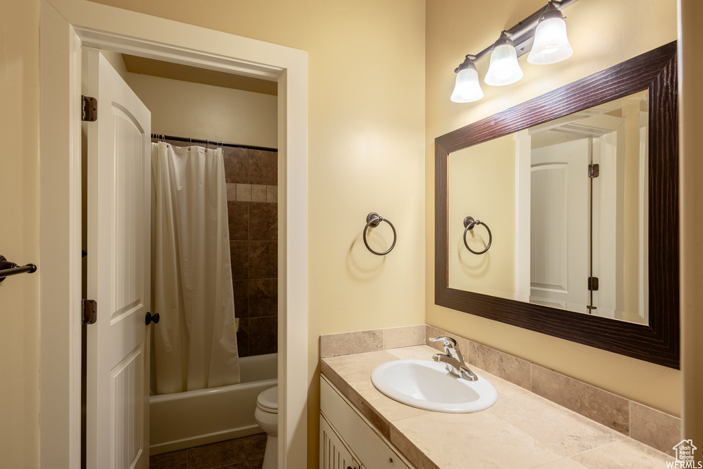 Bathroom featuring vanity, toilet, and shower / bathtub combination with curtain
