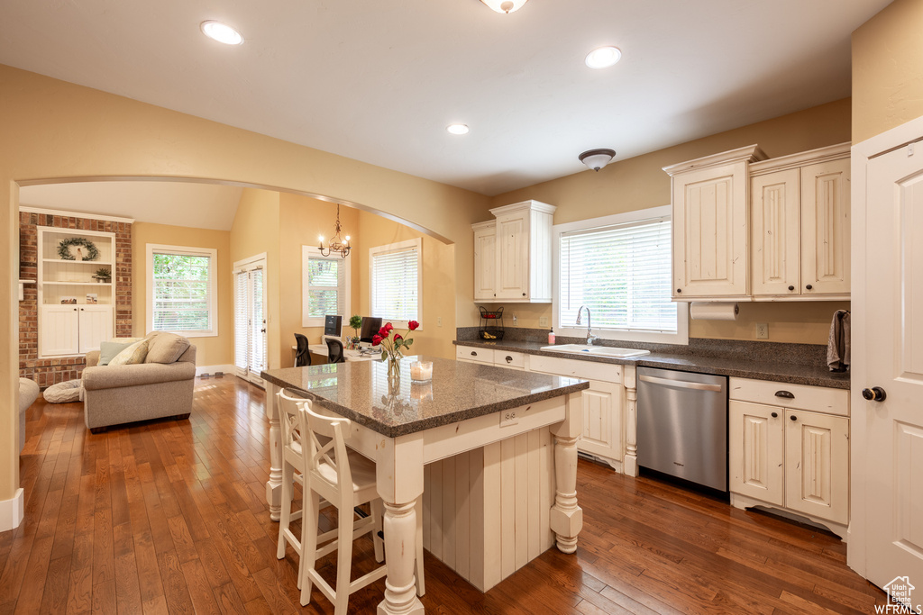 Kitchen featuring dishwasher, a sink, arched walkways, dark wood-style floors, and open floor plan