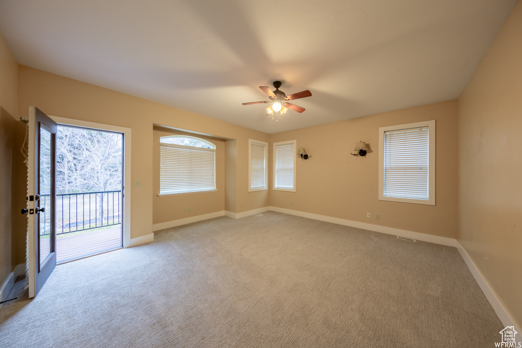 Carpeted empty room featuring ceiling fan and baseboards