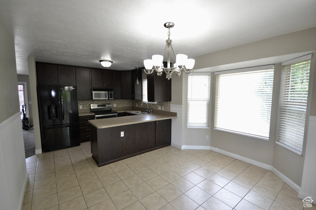 Kitchen with stainless steel appliances, a sink, a chandelier, a peninsula, and healthy amount of natural light
