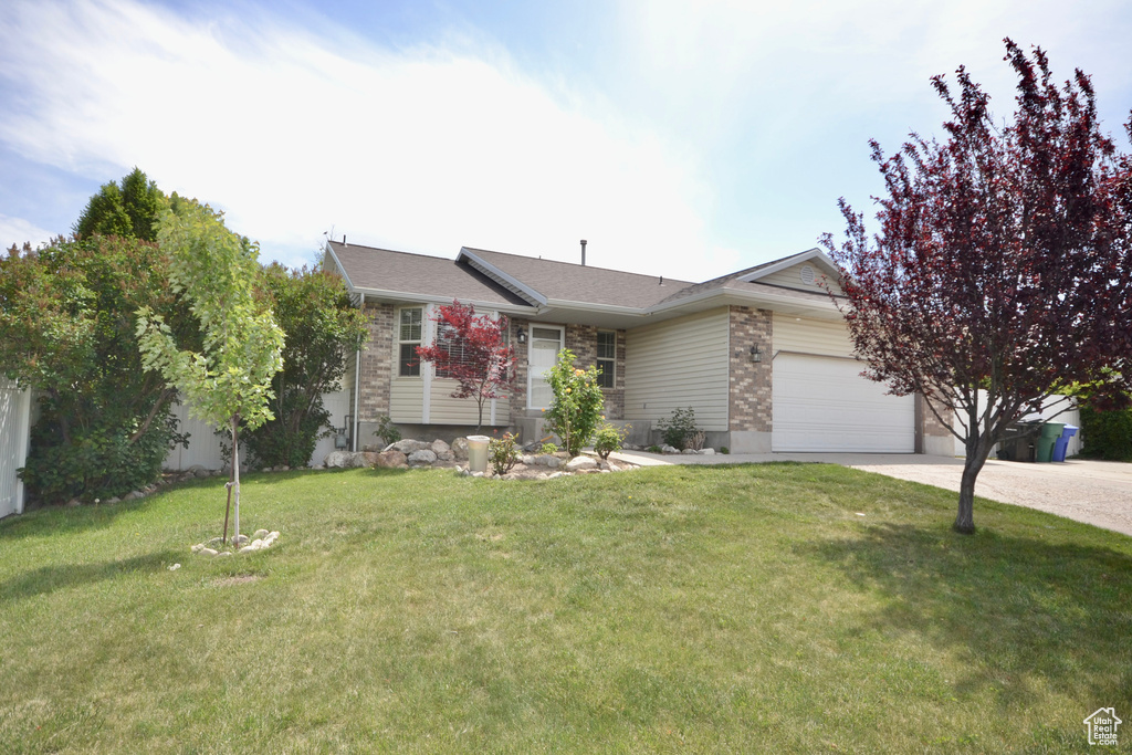 View of front of property with driveway, a garage, a front lawn, and brick siding